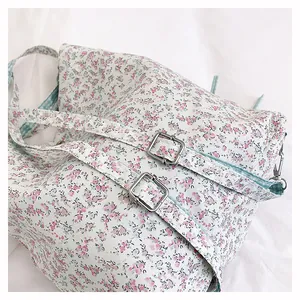 Close-up of floral cotton bucket bag with silver metal buckles and blue checkered straps