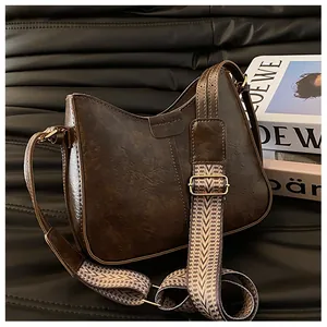 Detail view of a vintage dark brown shoulder bag with a textured geometric woven strap
