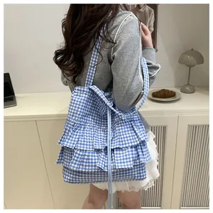 Blue and white gingham tote bag with ruffled edges shown on model's shoulder