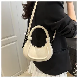 Detailansicht der cremefarbenen Halbmond-Tasche mit FASHION-Prägung und Bogen-Griff