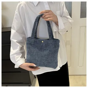 Detail of dark blue woven tote bag with golden metal buckle clasp and sturdy handle