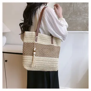Detalle del bolso de paja tejida con correa de cuero y borlas decorativas en el lateral