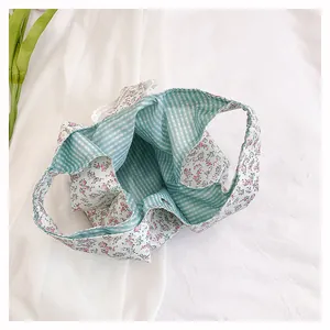 Detail view of floral cotton tote bag with green gingham lining and lace trim edge