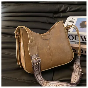 Detail of a brown vintage hobo bag with dual straps on a premium black leather surface