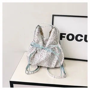 Detail of floral drawstring backpack with pink flowers, blue plaid bow and metal buckle