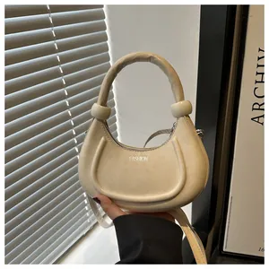 Detail der beige Halbmondtasche mit Rundgriff und silbernem Fashion-Schriftzug vorne