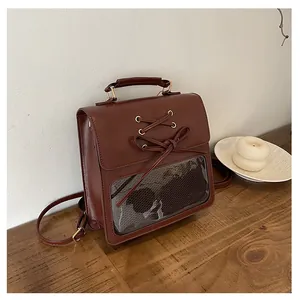 Detailed view of brown faux leather backpack with bow tie and transparent PVC window