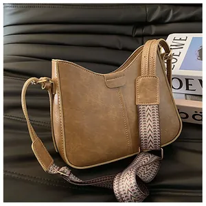 Detail of vintage brown bucket bag with wavy edge and patterned wide shoulder strap