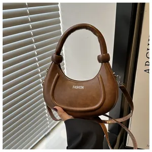 Details der dunkelbraunen Halbmondtasche mit silbernem Fashion-Logo und Knotengriff
