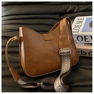 Detail of vintage brown bucket bag with textured leather and woven chevron shoulder strap