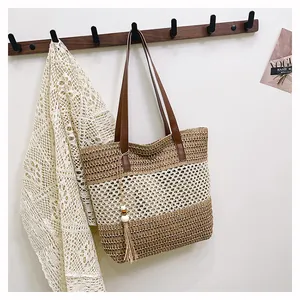 Detalle del bolso de paja con correas de cuero marrón y borlas decorativas en el lateral