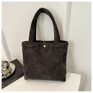 Detailed texture of dark grey corduroy tote bag with elegant golden metal buckle