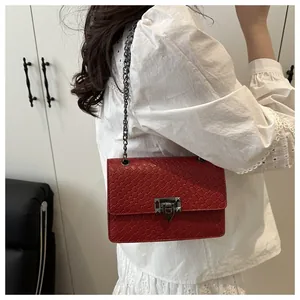 Bolso bandolera rojo con textura tejida y cadena metálica sobre top de encaje