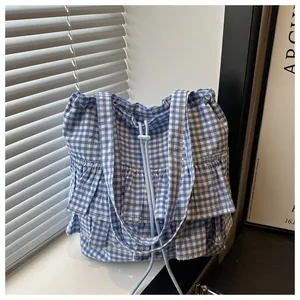 Detailed view of blue gingham tote bag with ruffle trim and drawstring on a windowsill