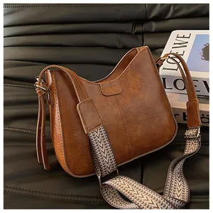 Macro detail of brown retro bucket bag with patterned woven strap on leather background