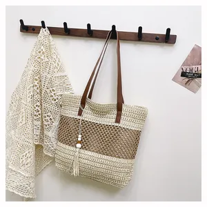 Detalle del bolso tote de paja tejido con rayas en contraste y adorno de flecos