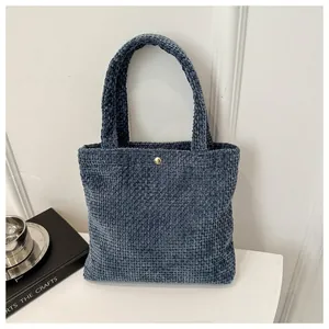 Close-up of deep blue knitted tote bag showing square texture and gold buckle