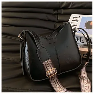 Close-up of black leather shoulder bag featuring a geometric patterned woven strap