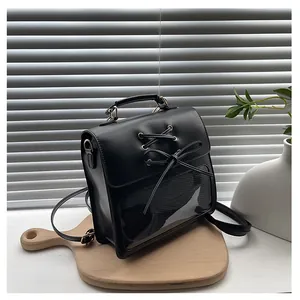 Detail of black faux leather mini backpack with transparent window and bow on wood tray