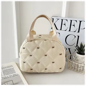 Detail of quilted beige handbag featuring brown bow patterns and woven handles