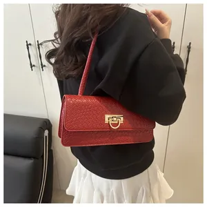 Detalle del bolso rojo con patrón de cocodrilo y elegante cierre de metal dorado liso