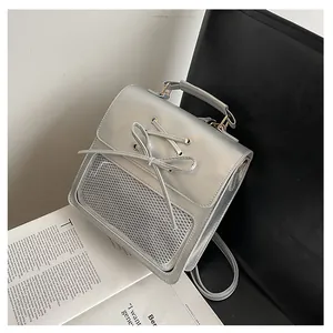 Detail of silver metallic backpack with rope bow tie and grey mesh stitching on a chair