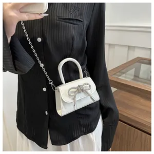 Close-up of a silver glitter mini bag with rhinestone bow and elegant chain strap