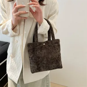 Minimalist dark brown woven tote bag with a golden round buckle for daily commute
