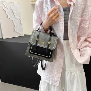 Sac à dos vintage gris avec boucles dorées porté par un mannequin en tenue décontractée