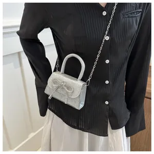On-body view showing the silver sequin mini bag with diamond bow and chain strap
