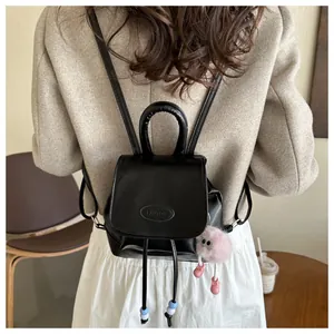 Rear view of black PU leather mini backpack with pink plush charm and drawstring