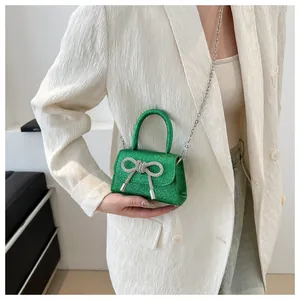 Close-up of green sequin mini bag with silver rhinestone bow and chain strap