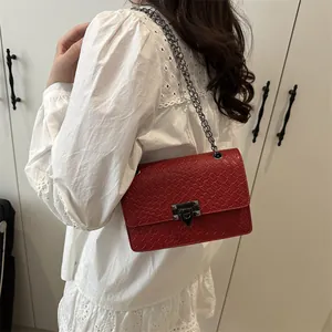 Elegante bolso cuadrado trenzado rojo con cadena y hebilla de metal visto de lado