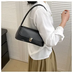 Detail of minimalist black leather shoulder bag with elegant gold metallic clasp and strap