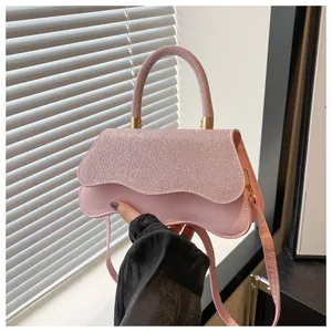 Detail van lichtroze schoudertas met glitterklep en metalen cilindrische handgreep