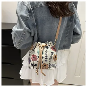 Foto lifestyle di una borsa a secchiello retrò a fiori con tracolla in pelle marrone