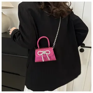 Detail view of pink sequin crossbody bag with silver diamond bow on a black blazer