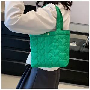 Detail of bright green tote bag featuring quilted heart patterns and matching handle