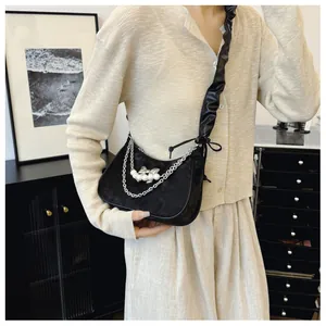 Detail of black crescent shoulder bag with silver chain and pearl bow charm