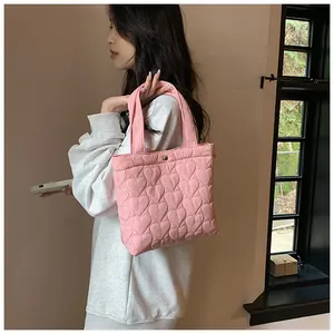 Close-up of pink quilted tote bag showing heart-shaped texture and metallic button closure