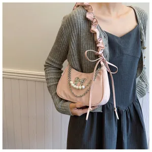 Detail of pink crescent bag featuring silver bow, pearls and wavy pleated strap