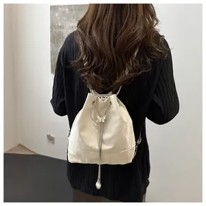 Détail d'un sac à dos blanc à cordon avec breloque papillon porté par un mannequin