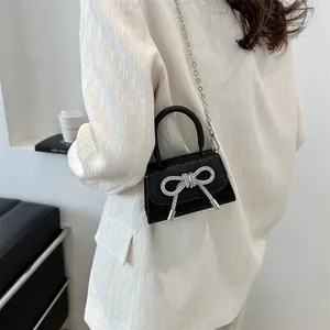Mini sequin crossbody bag with oversized silver bow and chain strap in black