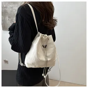 Détail du sac seau blanc à cordon avec boucle papillon et finition texturée élégante