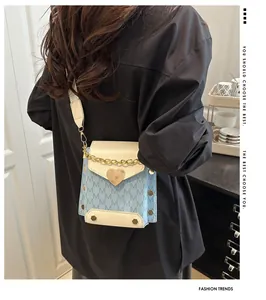 Detail of mini crossbody bag with heart buckle, chain accents and rivet textures
