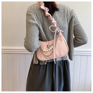 Detailed view of pink crescent bag with metal bows, pearls, and ruffled shoulder strap