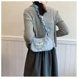 Detail of light blue crescent underarm bag with pearl chain and silver bow charm