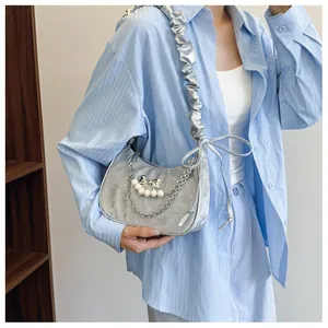 Detail of silver crescent shoulder bag featuring pearl bow charms and pleated strap