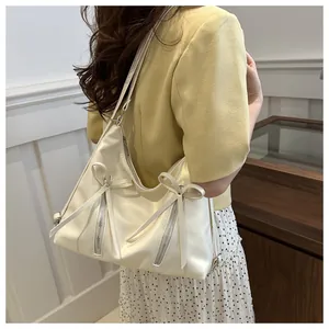 Detail showing the white bow ribbons and functional metal double zippers on the tote bag