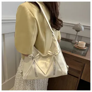 Dettaglio della borsa hobo bianco crema con cerniere decorative e accenti di fiocchi